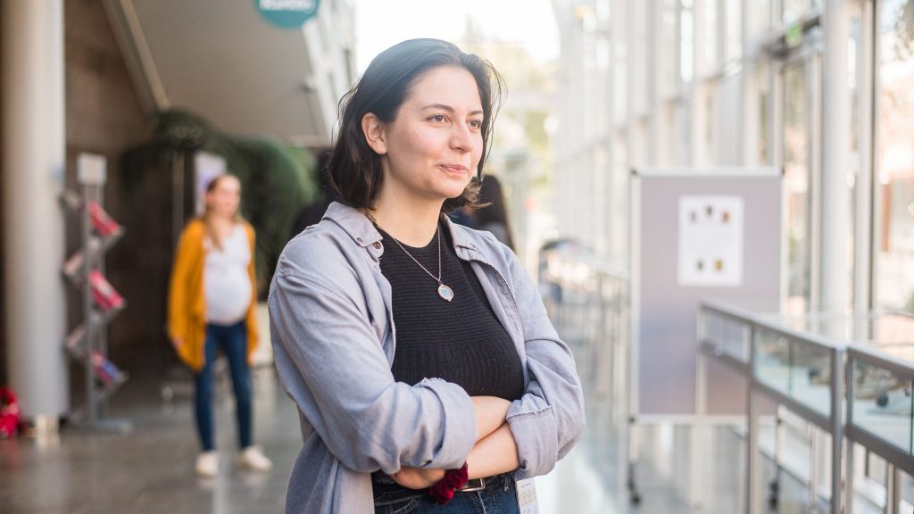 Nainen katsoo pieni hymy kasvoilla kädet päättäväisesti puuskassa tulevaisuuteen.